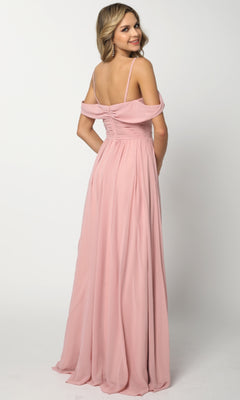 A woman, smiling as she faces backward, wears the Juliet 676 long prom dress—a blush pink chiffon gown featuring an A-line skirt and delicate spaghetti straps.