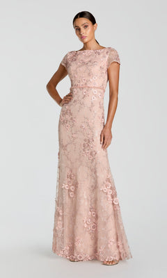 A woman in the Long Formal Dress 67711 by Mac Duggal, featuring fitted lace with floral embroidery and delicate appliqué, stands against a plain light background.