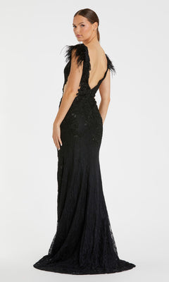 Woman wearing the Black Embroidered Formal Gown: Mac Duggal 67782, featuring feathered shoulder details, stands with her back partially to the camera against a plain white background.