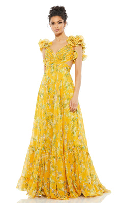 A woman models the Mac Duggal 67803 Ruffled Long Print Formal Dress, featuring yellow floral patterns and ruffled shoulders, standing against a plain white background.