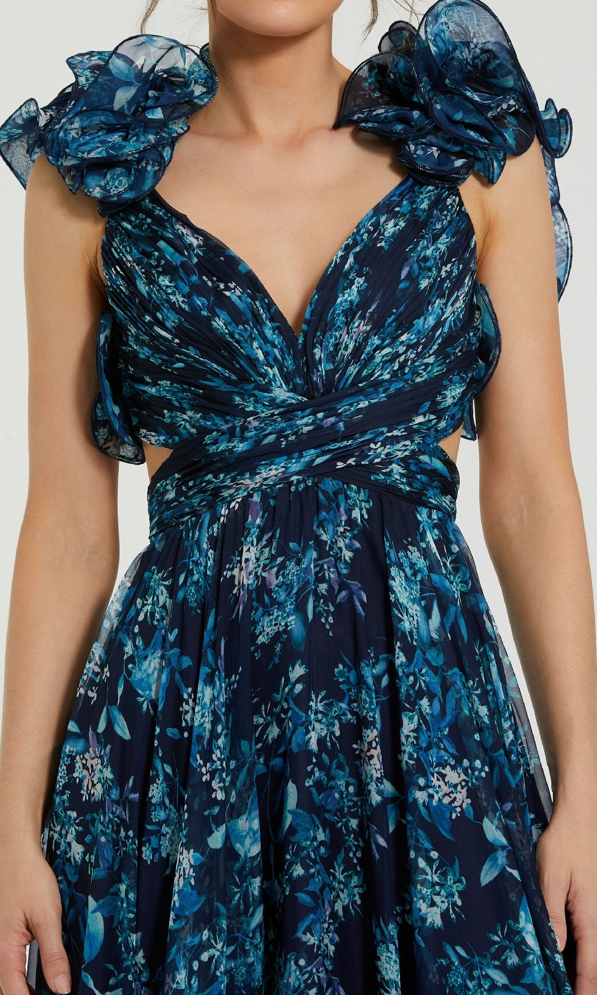 A woman wearing the Mac Duggal 67803 Ruffled Long Print Formal Dress—navy blue with floral print, deep V neckline, ruffled shoulders, cutout sides, and a flattering A-line silhouette.
