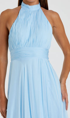 A person wearing the Mac Duggal 67816 Open-Back Halter Formal Dress, a sleeveless, light blue gown with a high neck, pleated skirt, and fitted waistband.
