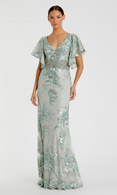 A woman wears the Mac Duggal 67842 Flutter-Sleeve Long Formal Dress—pale green, floor-length with floral embroidery, flutter sleeves, and a V-neckline—standing against a plain white background.