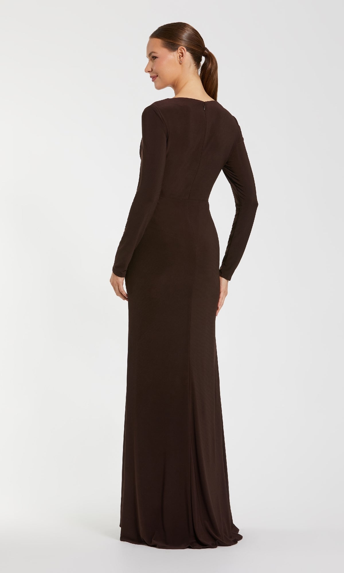 A woman faces away, hair in a low ponytail, wearing the Mac Duggal 67848 long sleeve, floor-length formal dress in brown against a plain white background.