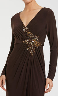 A woman stands against a plain background in the Mac Duggal 67848, a long sleeve formal dress featuring a V-neck and gold and brown beaded waist embellishments.