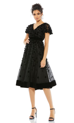 A woman wearing the Mac Duggal 67854 Floral Midi Wedding Guest Dress with black floral embellishments, short sleeves, and vintage knee-length style stands in heels against a plain white background.