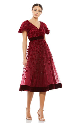A woman in the Mac Duggal 67854 Floral Midi Wedding Guest Dress with short sleeves and velvet waistband pairs it with nude heels, creating a charming vintage-inspired look.