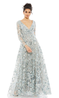 A woman wears the Mac Duggal 67869 Long Sleeve Lace Formal Dress, featuring a light blue-grey color, floral embroidery, sheer long sleeves, and a deep V-neck—an ideal mother of the bride gown.