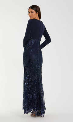 A woman faces away in the Mac Duggal 67871 long sleeve dark blue formal gown, featuring sequins and lace embroidery, paired with silver heels against a plain background.