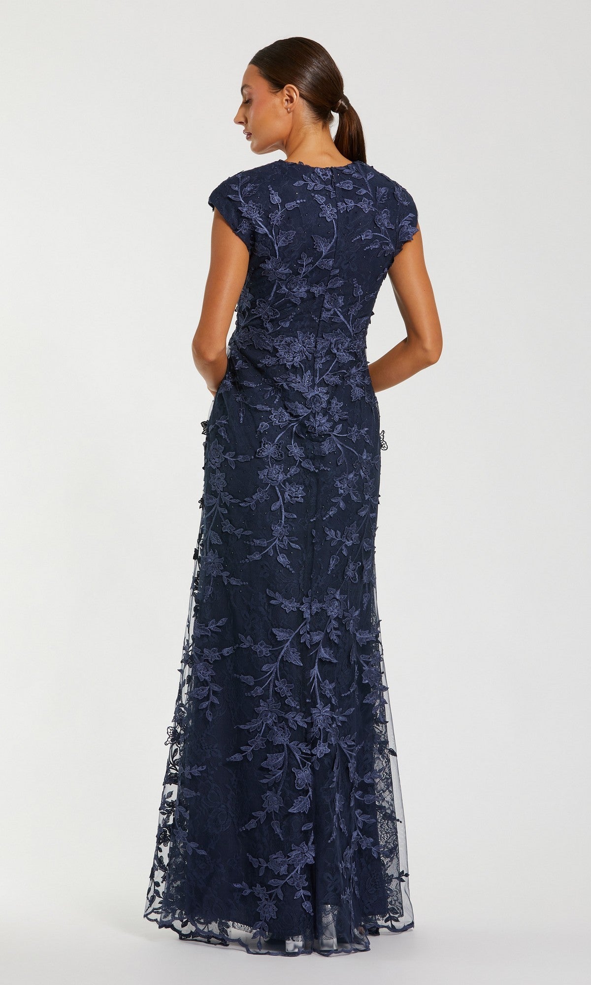 A woman faces away, wearing the floor-length Mac Duggal 67882 long formal dress, featuring short sleeves and a stunning embroidered mesh lace overlay.