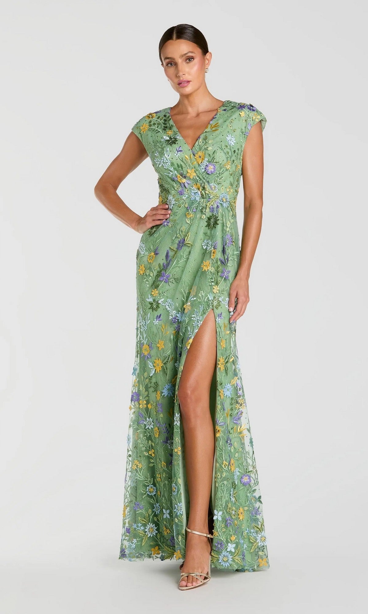 A woman in the Mac Duggal 67882 Cap Sleeve Long Blue Formal Gown stands against a plain light background.