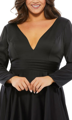 Smiling warmly with hands lightly clasped, a woman wears the Plus-Size Black Knee-Length Party Dress 67907, featuring long sleeves and a deep V-neckline.