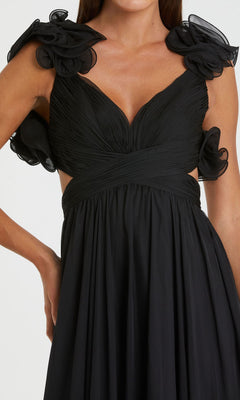 Woman wearing the Mac Duggal Empire-Waist Cut-Out Formal Dress 67911, a sleeveless black v-neck gown featuring a pleated bodice, floral ruffle shoulders, cutout sides, and a deep neckline.