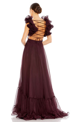 Woman in the Mac Duggal Empire-Waist Cut-Out Formal Dress 67911, a floor-length, sleeveless dark burgundy gown with ruffled shoulders, lace-up crisscross open back, and her hair styled in a bun.