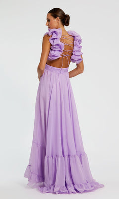 A woman wears the Mac Duggal Empire-Waist Cut-Out Formal Dress 67911, a long light purple gown with lace-up open back and ruffled sleeves, featuring an elegant silhouette, standing against a plain background.