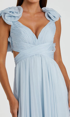 A woman wears the Mac Duggal Empire-Waist Cut-Out Formal Dress 67911—a light blue, sleeveless gown with pleated fabric, floral shoulder accents, and side cut-outs.