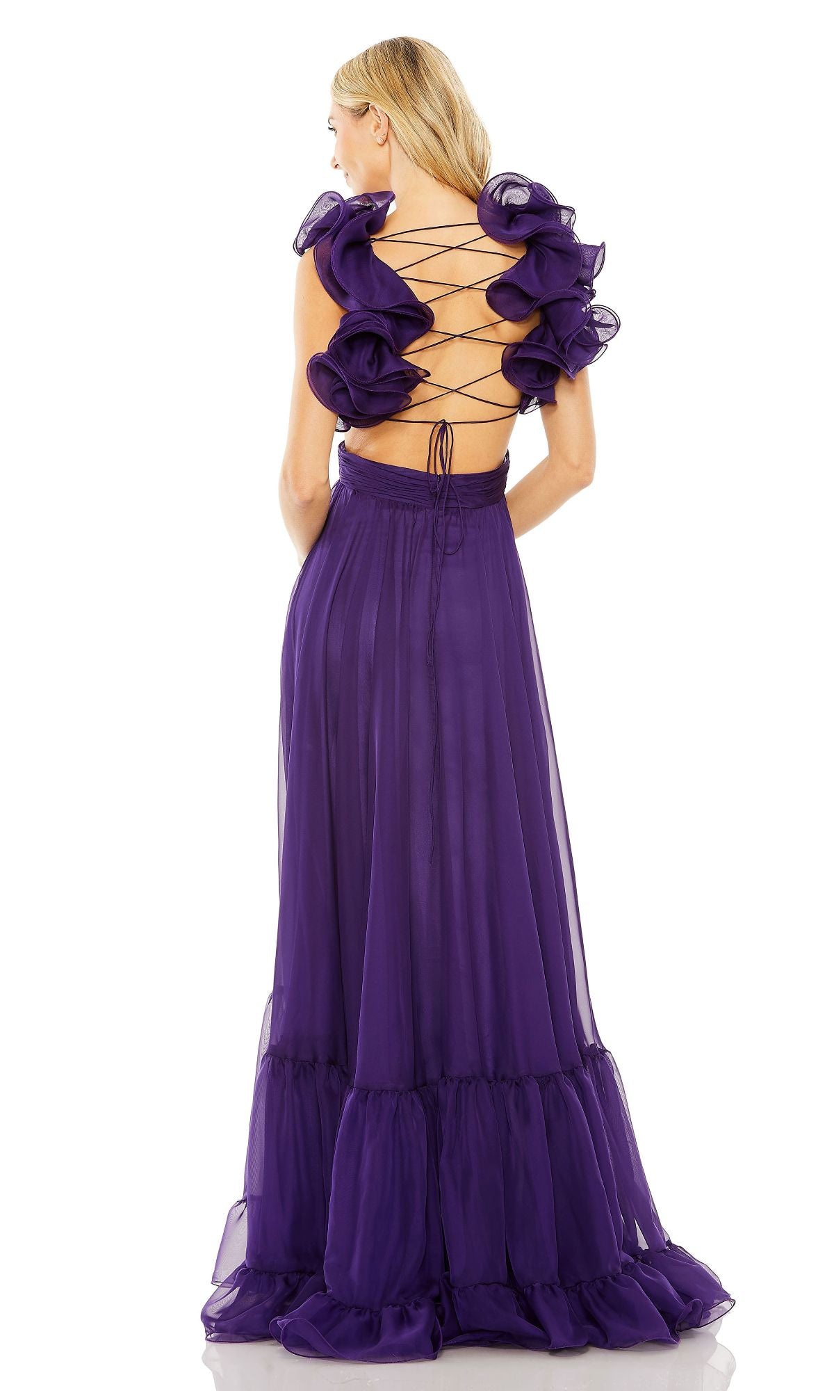 A woman stands facing away, wearing the Mac Duggal Empire-Waist Cut-Out Formal Dress 67911, a floor-length purple gown featuring ruffled sleeves, a v-neckline, and a lace-up open-back design.