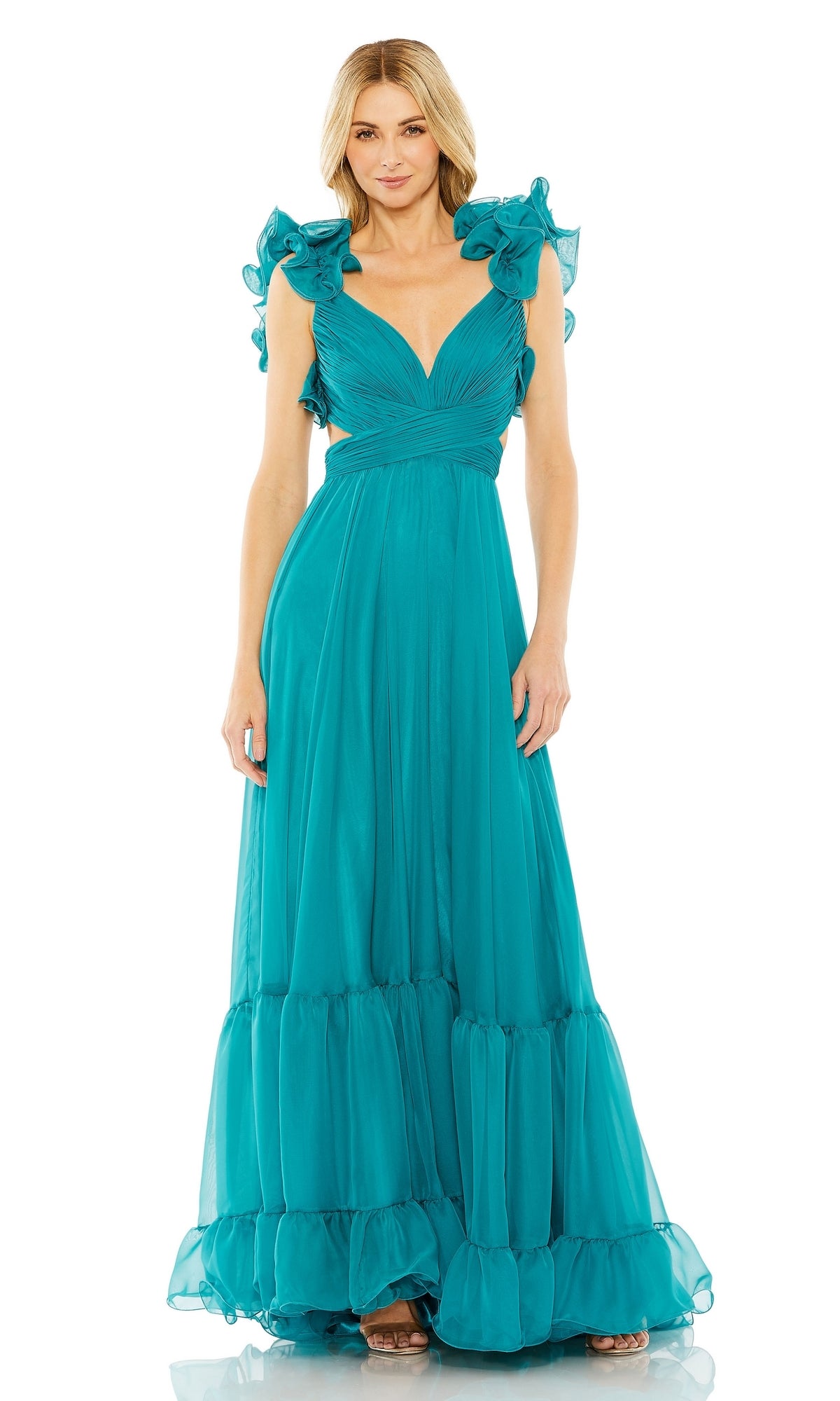 A woman wears the Mac Duggal Empire-Waist Cut-Out Formal Dress 67911, a floor-length teal gown featuring a v-neckline, ruffled sleeves, and a deep cut-out detail.