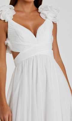 A woman wears the Mac Duggal Empire-Waist Cut-Out Formal Dress 67911, featuring a white v-neck design with a deep V neckline, pleated bodice, floral shoulder accents, and a flowy skirt.