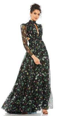 A woman models the Mac Duggal 67942 long black print formal dress, featuring sheer long sleeves and a high neckline, set against a white background.