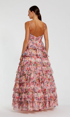 A woman faces away in the Mac Duggal 67966 Violet Print Prom Ball Gown, a sleeveless, floor-length dress featuring multiple ruffled tiers and a vibrant floral pattern.