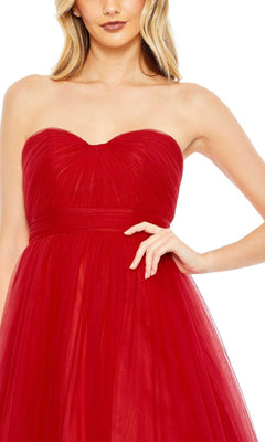 A woman wears the Long Formal Dress 67999 by Mac Duggal, a strapless red tulle ball gown, shown from mid-face to waist with one hand on her hip.