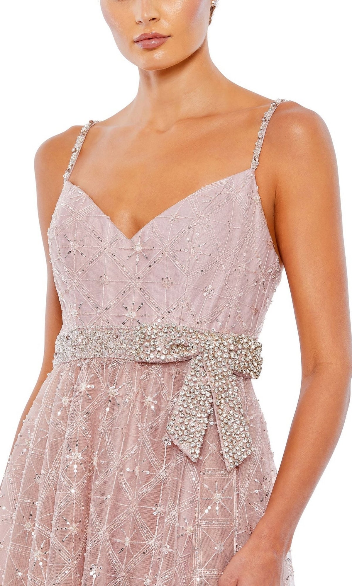 A woman wears the Long Formal Dress 68050 by Mac Duggal in rose pink, featuring thin straps, intricate bead detailing, and an embellished bow belt at the waist.