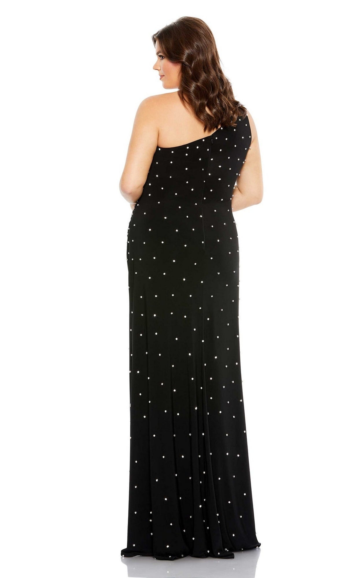 A woman wearing the Mac Duggal 68130 Plus-Size One-Shoulder Prom Gown, featuring a dotted pattern, stands facing away with her hair down, radiating modern elegance.