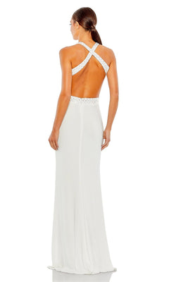 A woman stands facing away in the Long Formal Dress 68166 by Mac Duggal, featuring a fitted silhouette, open back, and crisscross straps.