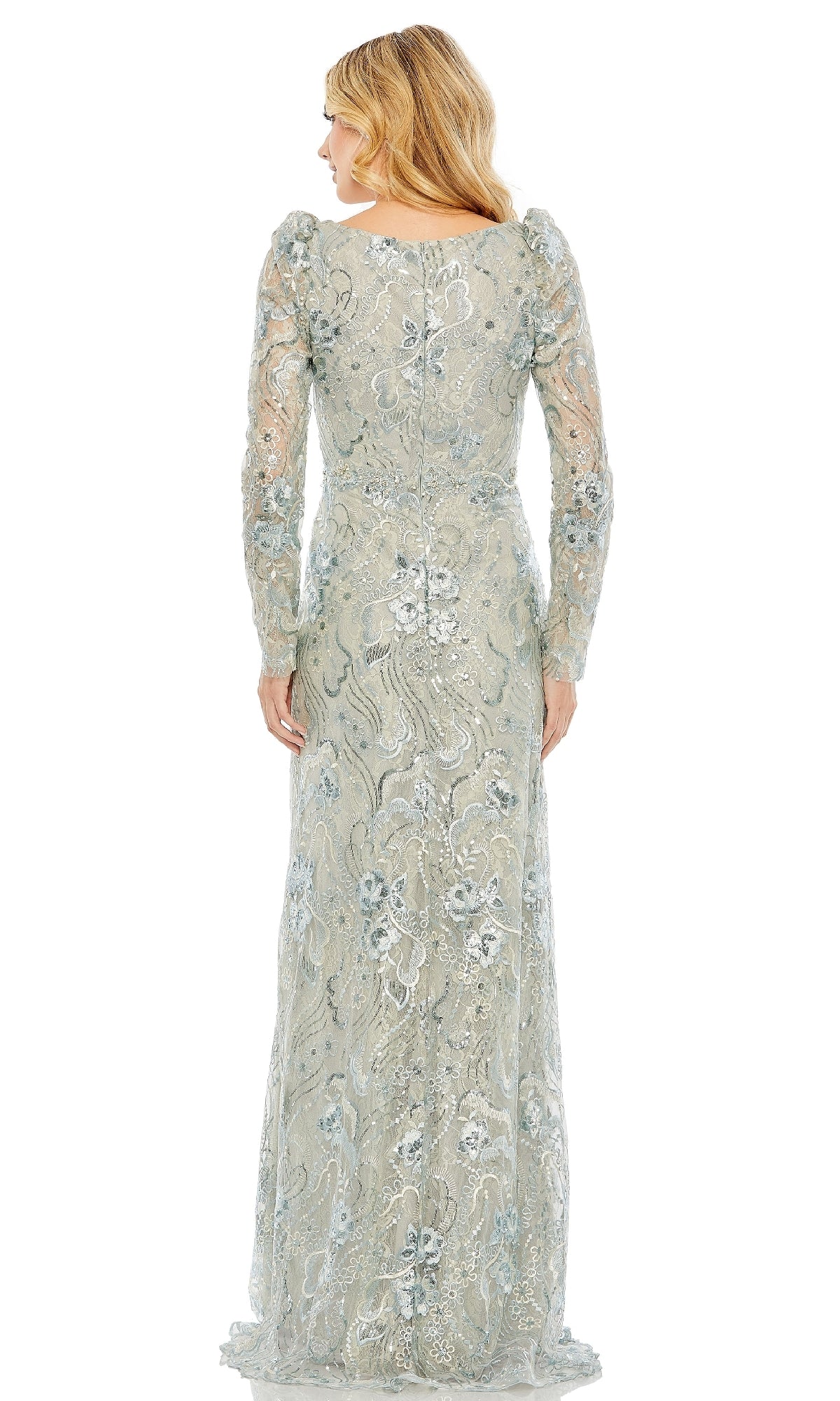 Woman stands with her back to the camera in the Mac Duggal 68190 long sleeve beaded formal dress, featuring a fitted waist and silver lace with floral patterns, exuding timeless elegance.