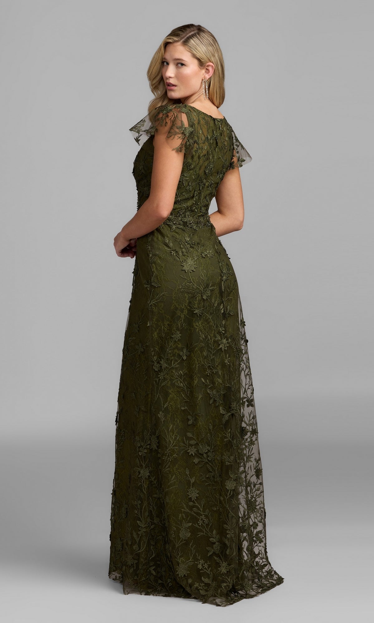 A woman wearing the Long Beaded Formal Dress: Mac Duggal 68192 in olive green stands with her back to the camera, turning her head over her shoulder against a plain gray background.