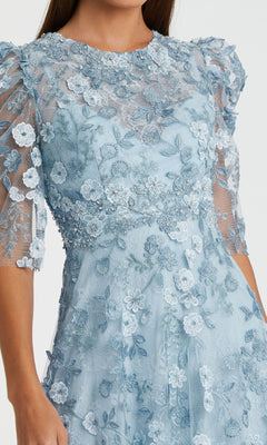 A woman wearing the Mac Duggal 68193 Tea-Length Lace Formal Dress in light blue with floral embroidery and sheer puff sleeves.