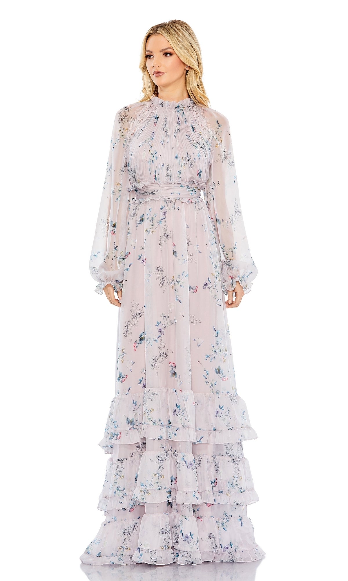 A woman wears the Long Formal Dress 68199 by Mac Duggal, featuring a lilac floral print, sheer long sleeves, tiered ruffle skirt layers, and an elegant A-line silhouette with a high neckline.