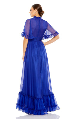 A woman faces away, wearing the Mac Duggal 68229—a royal blue sheer long formal dress with short ruffled sleeves and hem—standing against a white background.