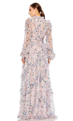 A woman stands facing away, wearing the Mac Duggal Long Formal Dress 68232, featuring blush color, long ruffled layers, and sheer sleeves. Her hair is styled in a low ponytail.