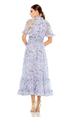 A woman faces away in the Mac Duggal 68259 Lilac Floral Print Formal Dress, an a-line midi with sheer short sleeves and ruffle details, styled with beige high-heeled shoes.