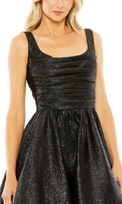 A woman wears the Mac Duggal 68349 Long Glitter Prom Ball Gown, featuring a sleeveless design, textured black fabric, square neckline, and fitted bodice.