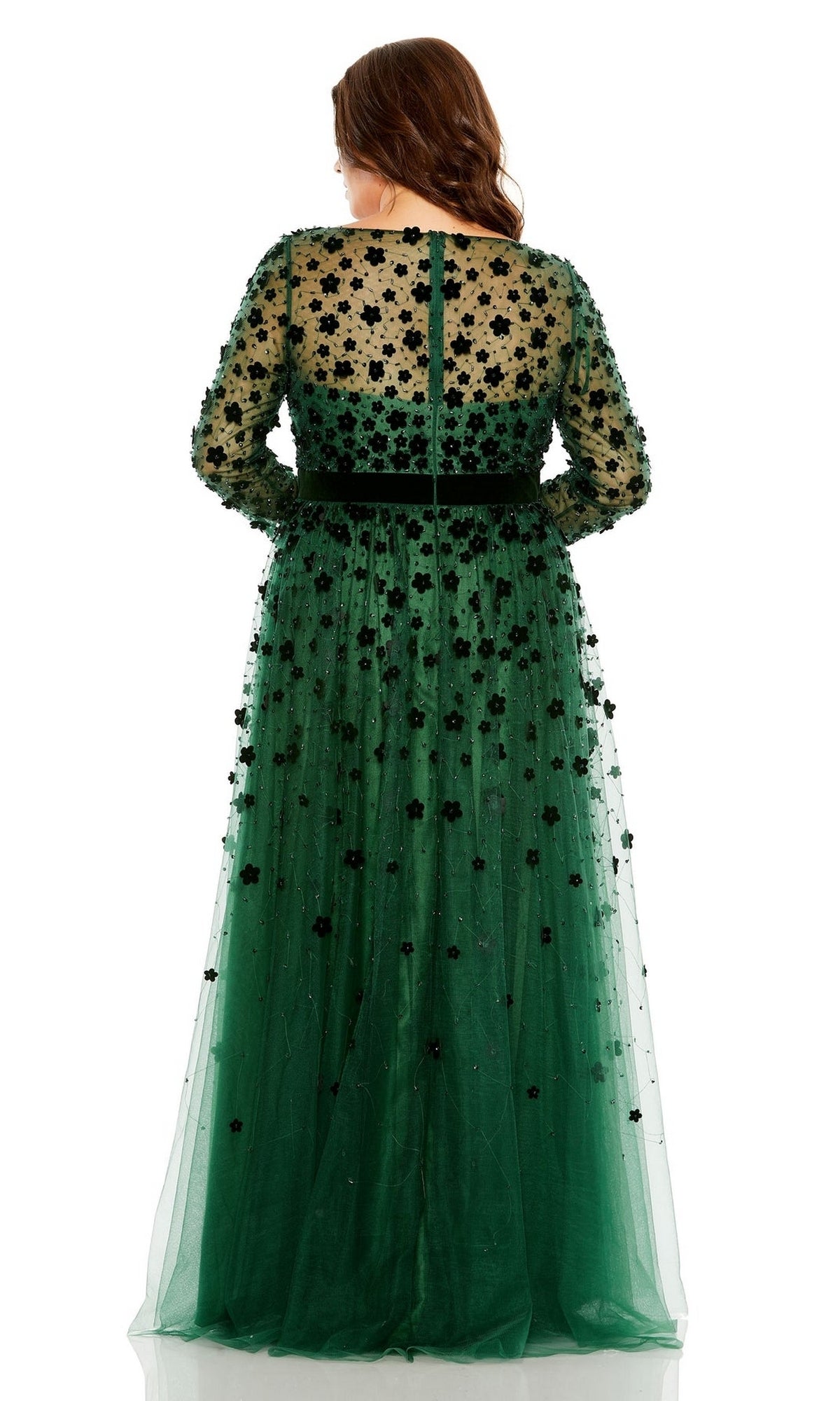 A woman faces away, wearing the Long Plus-Size Prom Dress 68440 by Mac Duggal—a floor-length green gown with sheer sleeves and a floral appliqué overlay.