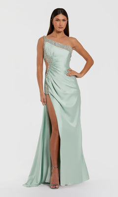 A woman wearing the Mac Duggal 68447 long formal dress in sage—a light green satin one-shoulder gown with rhinestone details and a thigh-high slit—paired with silver high-heeled sandals, standing against a plain white background.