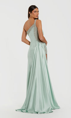 A woman stands and looks over her shoulder in the Mac Duggal 68447 long formal dress—a light green, one-shoulder satin gown featuring sequin accents and a draped train.