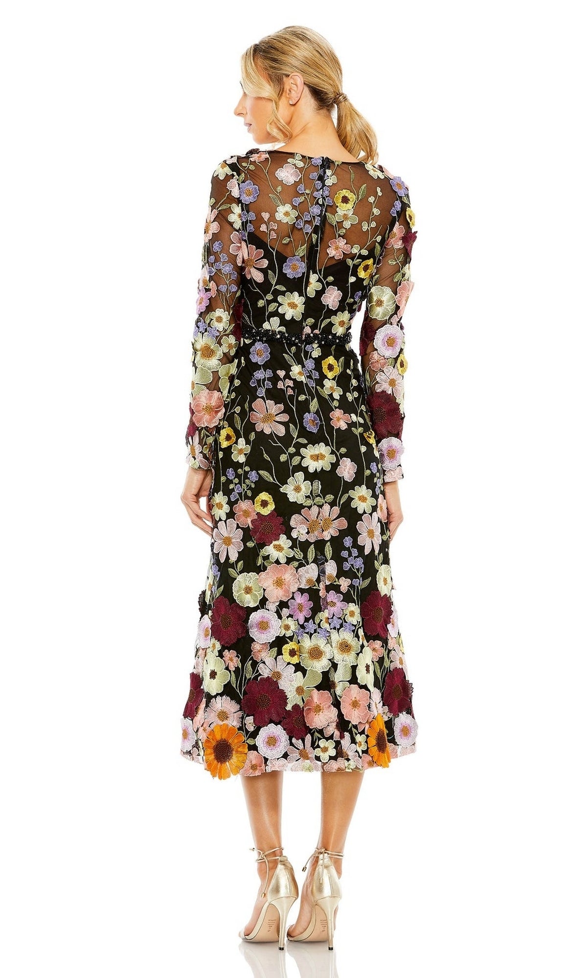 A woman faces away, wearing the Mac Duggal 68462 tea-length wedding-guest dress with sheer black floral print, multicolored embroidery, and beige high heels.