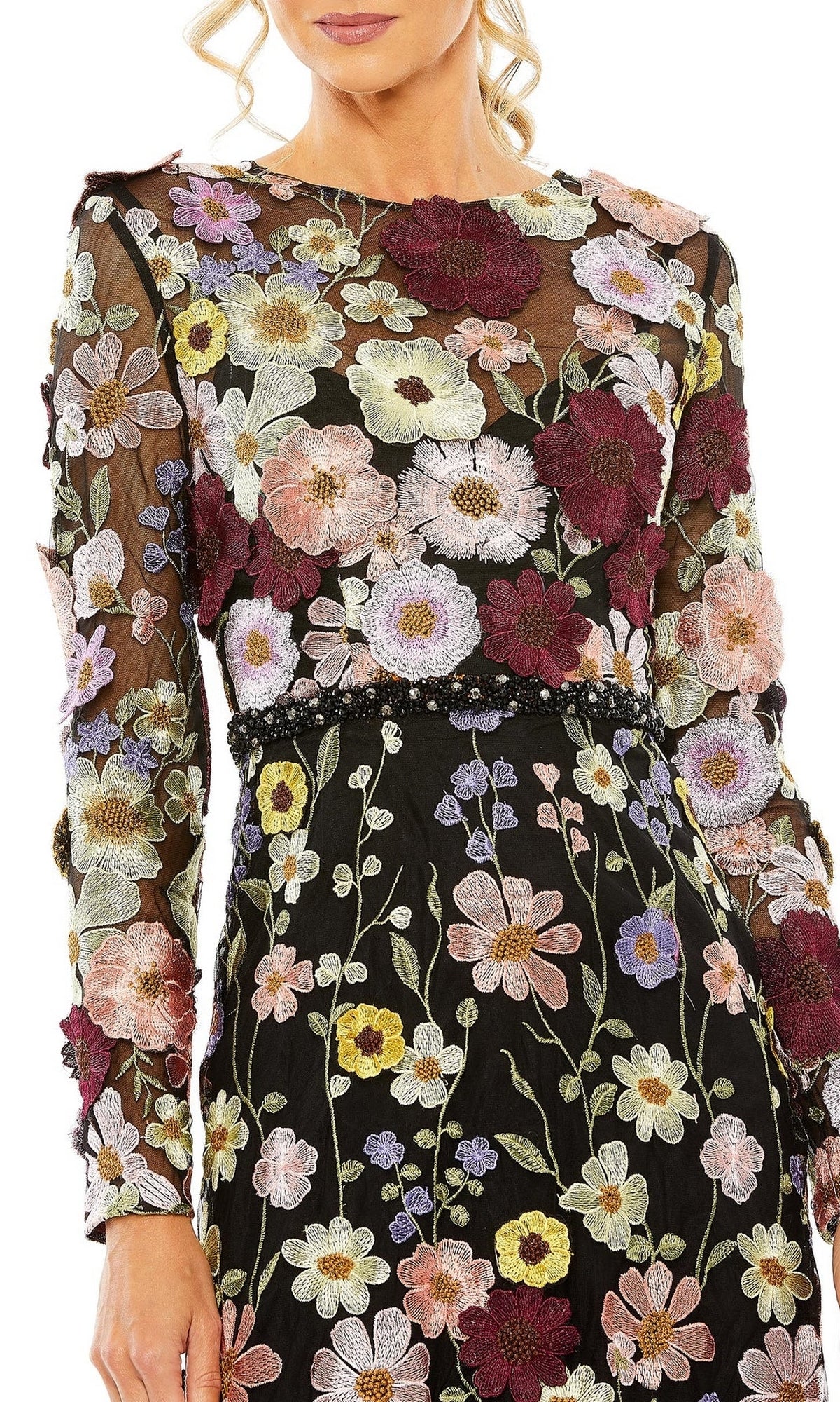 A woman wears the Mac Duggal 68462 tea-length wedding-guest dress, featuring long sleeves and colorful floral embroidery in purple, pink, yellow, and white.