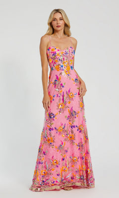 A woman stands against a plain background wearing the Long Formal Dress 68508 by Mac Duggal—a floor-length pink lace gown with colorful floral patterns and a sweetheart neckline.