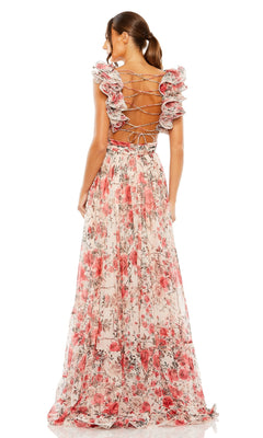 A woman models the Mac Duggal 68518 long formal dress, a pink floral chiffon gown with ruffle shoulders, open back, and lace-up detail, standing and facing away from the camera.
