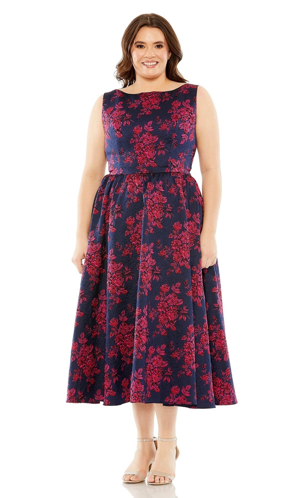 A woman smiles wearing the Plus-Size Knee-Length Print Party Dress 68557, a sleeveless navy blue dress with a red floral pattern, paired with beige heeled sandals.