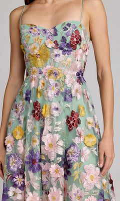 A woman wearing the Tea-Length Party Dress: Mac Duggal 68605, a sleeveless green midi dress with thin straps, colorful floral embroidery, a structured bodice, and an elegant A-line skirt, pictured from shoulders to knees.