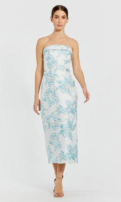 A woman wearing the Floral Midi Party Dress: Mac Duggal 68621 in French Blue and beige heeled sandals stands against a plain white background.