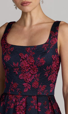 Woman wearing the Mac Duggal 68625 tea-length party dress in navy, featuring a sleeveless design with a square neckline and red floral embroidery, shown from shoulders to waist.