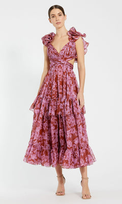 A woman wears the Mac Duggal 68644 red floral print chiffon formal dress with a tiered A-line skirt and cutout sides, paired with strappy high-heeled sandals, standing against a plain white background.