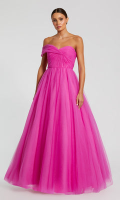 A woman wears the Mac Duggal 68713 One-Strap Long Prom Ball Gown, featuring a bright pink hue, fitted bodice, and full floor-length tulle skirt, posing against a plain background.
